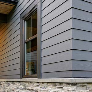 Close up view of a home with brown, vinyl  siding on it